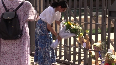 Scene from Ambasciata britannica, bandiere a mezz'asta e fiori per la regina dai passanti